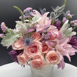 Pink roses and lilies in a textured vase with purple accents