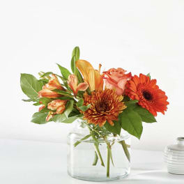 Orange and peach flowers arranged in a clear glass vase