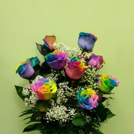 Rainbow-colored roses in a glass vase with white filler flowers