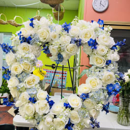 Heart-shaped floral wreath with white roses and blue flowers