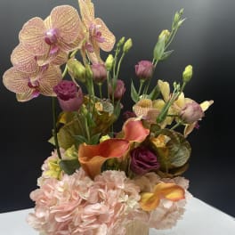 Mixed floral arrangement with orchids, calla lilies, and hydrangeas in a square vase