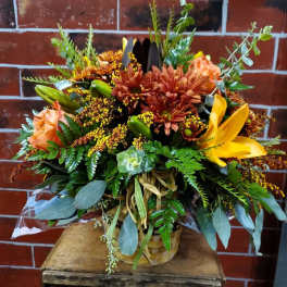 Basket arrangement with orange and yellow flowers and greenery