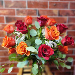 Bouquet of red and orange roses with eucalyptus in a vase