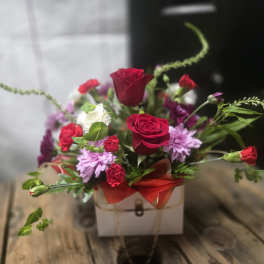Mixed bouquet with red roses and purple flowers in a white box