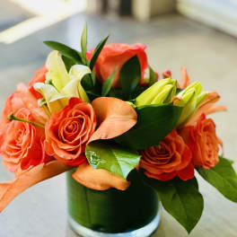 Orange roses and white lilies in a glass vase