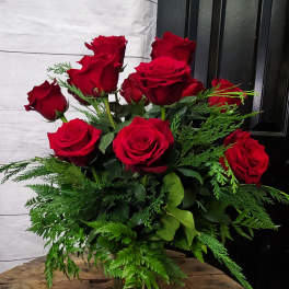 Bouquet of red roses in a clear glass vase with greenery