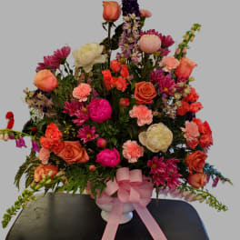 Large mixed bouquet in a white vase with a pink ribbon