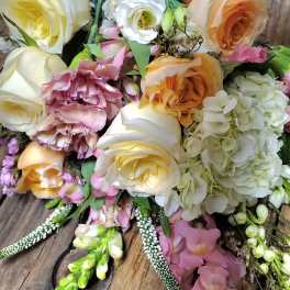 Bouquet of cream, peach, and pink flowers on a wooden surface