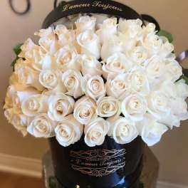 White roses arranged in a black hatbox with gold lettering