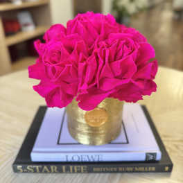 Bright pink roses arranged in a gold container on stacked books