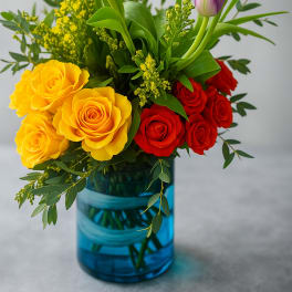 Bouquet of yellow and red roses with purple tulips in a blue vase