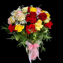 Bouquet of multicolored roses in a glass vase with a pink ribbon
