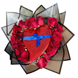 Red roses arranged around a heart-shaped box with a blue ribbon