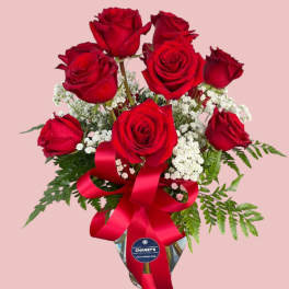 Bouquet of red roses with baby's breath in a glass vase and red ribbon
