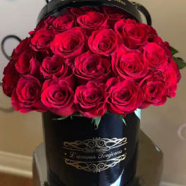 Red roses arranged in a black hatbox with gold lettering