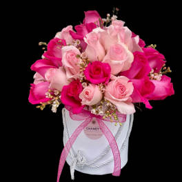 Pink and white roses arranged in a white hat box with a pink ribbon