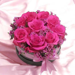 Pink roses arranged in a round hatbox with a ribbon