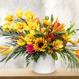 Tropical bouquet with yellow orchids, sunflowers, and bird-of-paradise in a white vase