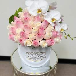 Pink and white roses with white orchids in a white hatbox