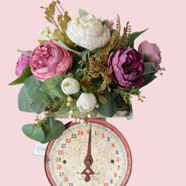 Pink and white flower arrangement on a vintage scale base