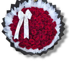 Large bouquet of red roses wrapped in black and white paper with a white bow