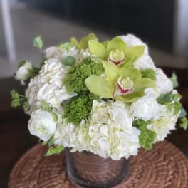 White floral arrangement with green orchids in a vase