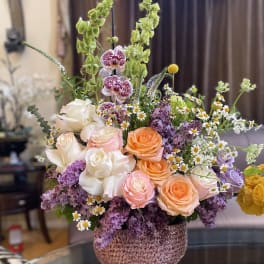 Mixed bouquet of roses, orchids, and small daisies in a textured vase