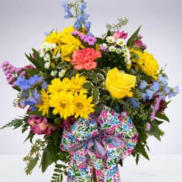 Bright mixed bouquet in a glass vase with a floral ribbon.