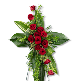 Tall cross-shaped arrangement of red roses with large green leaves on a standing easel.