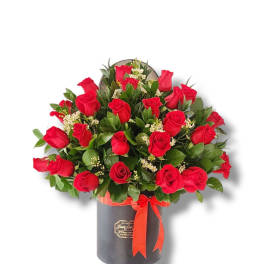 Red roses arranged in a black hatbox with a red ribbon