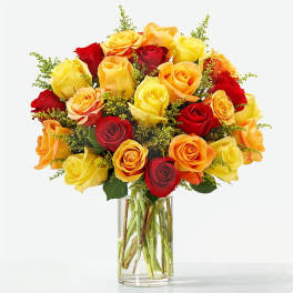 Bouquet of red, yellow, and orange roses in a clear glass vase