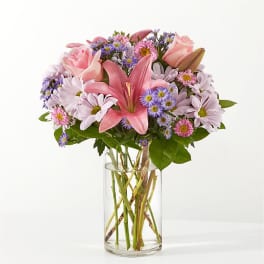 Pink lilies and daisies in a clear glass vase