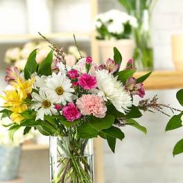 Mixed bouquet of daisies, carnations, and alstroemeria in a clear glass vase