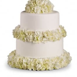 Three-tier white wedding cake decorated with white flowers