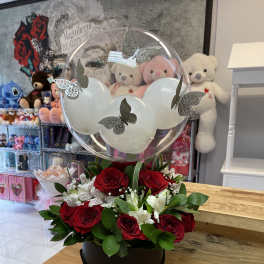 Red roses and white alstroemeria in a round box with a clear balloon topper