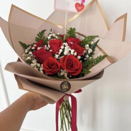 Bouquet of red roses with baby's breath and a small love note