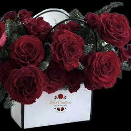 Red roses arranged in a white box with dark greenery