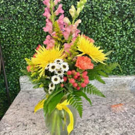 Mixed bouquet in a glass vase with yellow, pink, white, and coral flowers