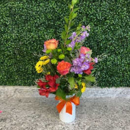 Mixed bouquet in a white vase with an orange ribbon