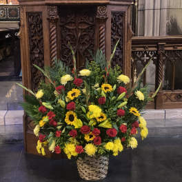 Large basket arrangement of red roses, yellow sunflowers, and lilies