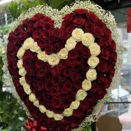 Heart-shaped rose arrangement with red and cream roses and a red ribbon