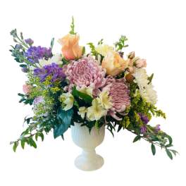 Pastel mixed flower arrangement in a white pedestal vase