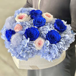 Blue and white roses arranged with pale blue hydrangeas in a heart-shaped box