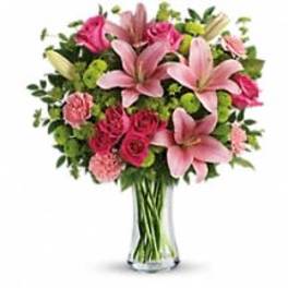 Pink lilies and roses arranged in a clear glass vase