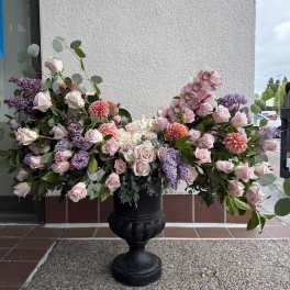 Large pink and lavender floral arrangement in a black urn
