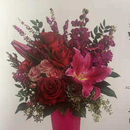 Bouquet of red roses and pink lilies in a tall pink vase