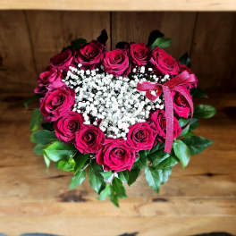 Heart-shaped bouquet of pink roses with white baby's breath and a pink ribbon