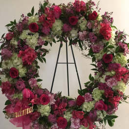 Large floral wreath with pink and white flowers on a black stand