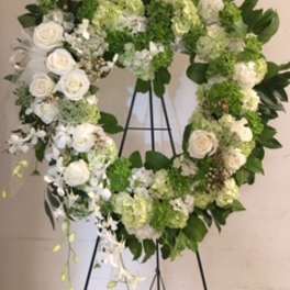 Heart-shaped floral wreath with white roses and green hydrangeas on an easel