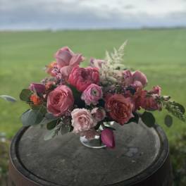 Pink and coral bouquet with roses and tulips on a barrel